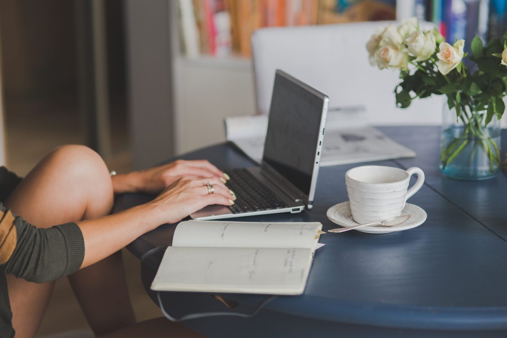 Person with planner or notebook with tea cup typing on a laptop